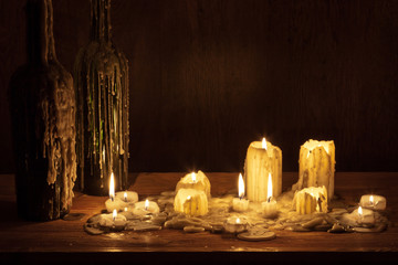 Melting candle in wooden shelf with bottle