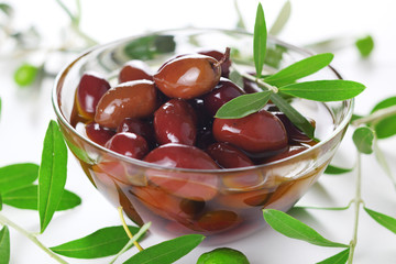 Black olives in olive oil and fresh leaves in close-up