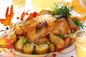 Whole roasted chicken with potatoes and apples on white plate
