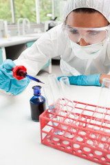 Portrait of a protected science student dropping blue liquid in