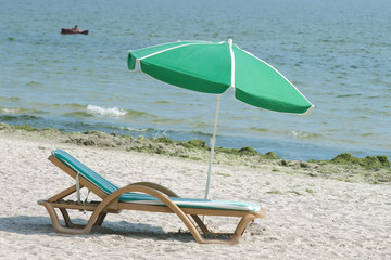 chaise longues and parasol on the beach with sea