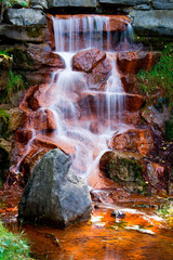 Waterfall Cascading Over Red Algae Covered Rocks