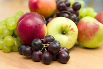 Naklejka na ściany i meble Świeże owoce, jabłka, winogrona i brzoskwinie na stole