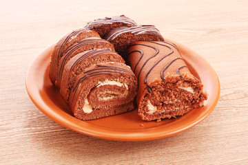 Swiss roll   on the  dish on wooden background