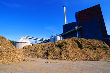 bio power plant with storage of wooden fuel against blue sky