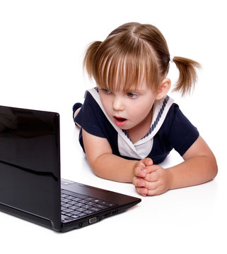 The surprised little girl looks in a laptop