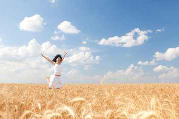 Naklejka na ściany i meble Happy woman jumping in golden wheat