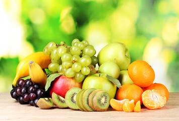 Ripe juicy fruits on wooden table on green background