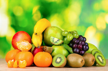 Ripe juicy fruit on wooden table on green background