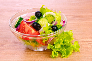 salad of fresh vegetables on the plate on wooden background