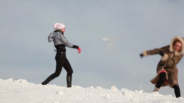 Girls are playing snowballs on slope with snow