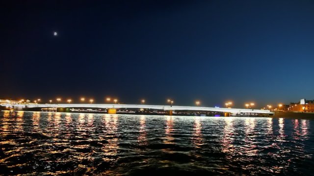 Camera moves under lighted Liteyny Bridge standing on Neva