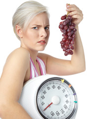Sad girl holding grapes and carrying set of scales