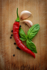 Red hot chili peppers, garlic and basil over wooden background