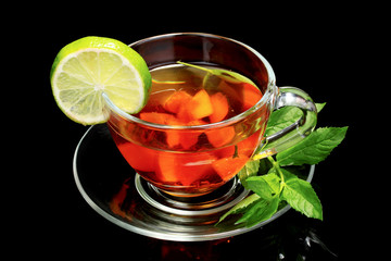 black tea and fruit in cup on black background