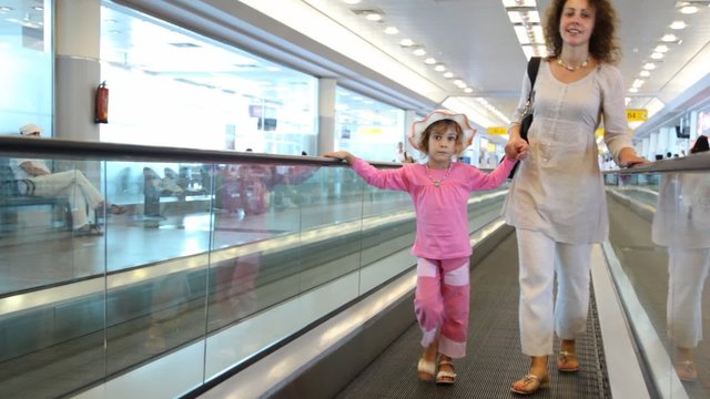 Woman and girl run on speedwalk at airport