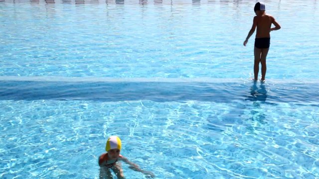 Boy jumped into the water, girl swims not far