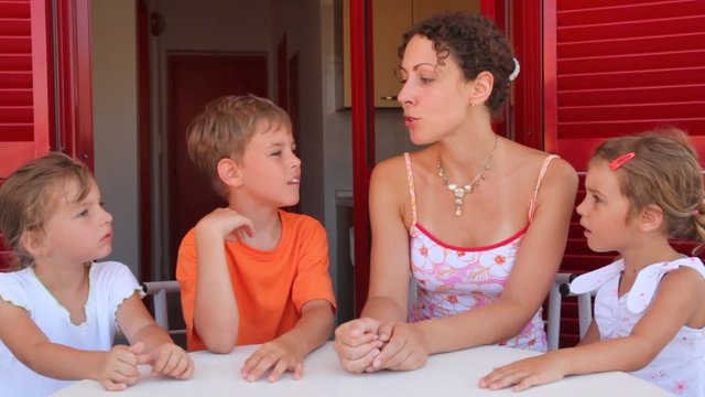 Woman and three kids are sitting at balcony