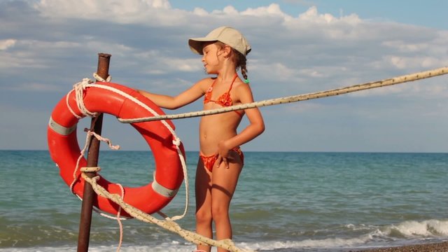 Girl puts a rope and poses next to lifebuoy ring