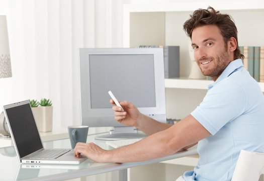 Man using computer and phone at home