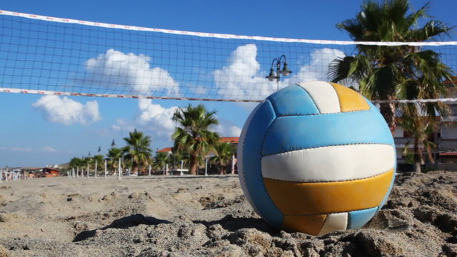 Ball lies on sand under volleyball net at beach