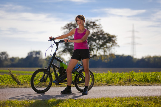 Frau steht mit Streetstepper auf Fahrradweg