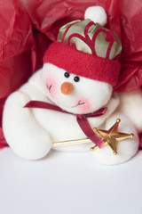 Smiling snowman on gift box with red tissue paper.
