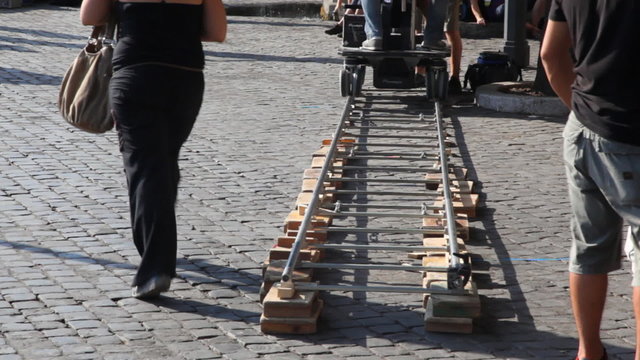 People running near cart on rails preparing to shooting film