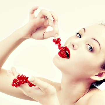 A woman seductively eating red berries.