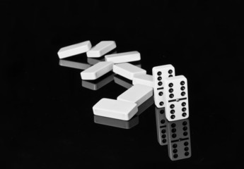 Black and white dominoes on black shining surface