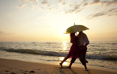Naklejka premium Couple kissing at the beach in sunset.