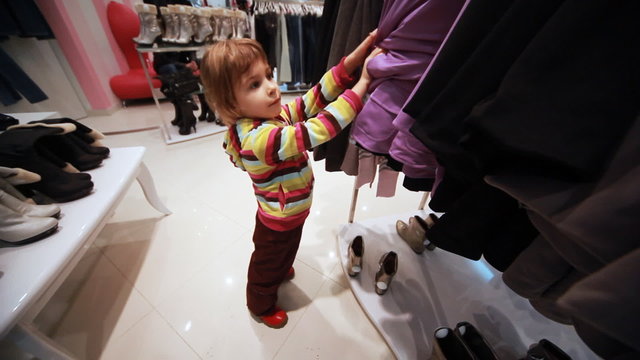 girl carefully choose clothes in shop