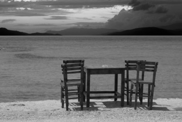 Empty wooden table and chairs on seafront