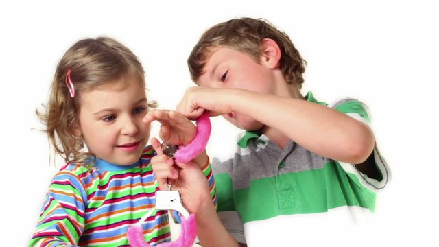 Two children plays with furry handcuffs