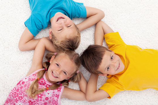 Three kids laying on the floor in circle