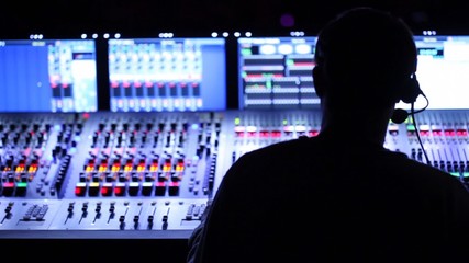 Silhouette of sound producer, which sits at mixer panel