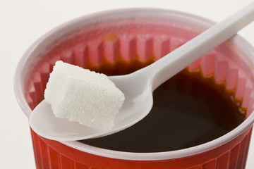Kaffee im roten Plastikbecher mit Würfelzucker
