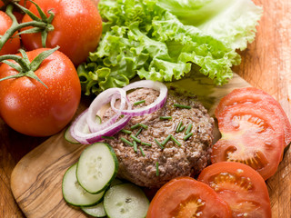 hamburger with slice vegetables over cutting board