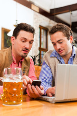 Zwei Freunde in bayerischer Wirtschaft mit Laptop