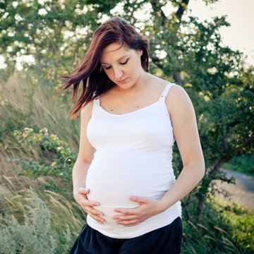 Pregnant woman in nature touching her belly