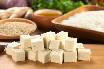 Raw tofu cut in dices on wooden board