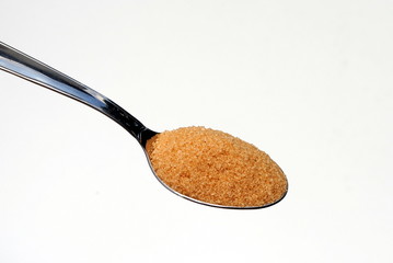 steel spoon filled with bown sugar