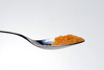 steel spoon filled with bown sugar
