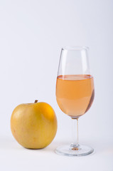 A glass filled with orange substance and an apple