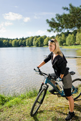 Obraz premium Mountain biking young woman relax by lake