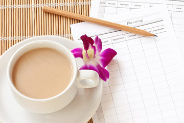 A cup of coffee with planning paper