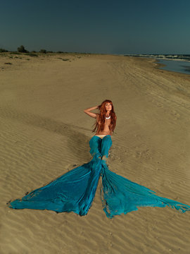 .beautiful red hair mermaid on deserted beach