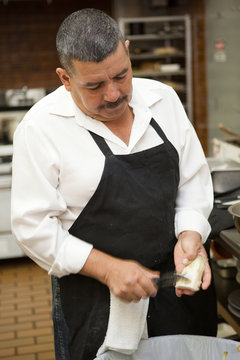 Hispanic kitchen worker peeling vegetables