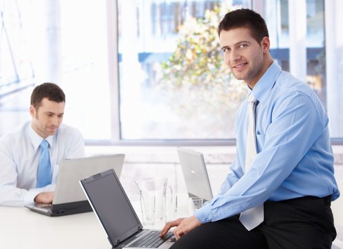 Young businessman using laptop smiling in office