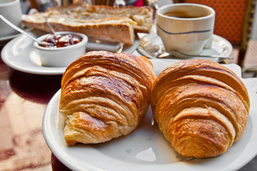 Breakfast with coffee and croissants in a basket on table